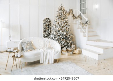 Modern living room with a Christmas tree decorated in silver and gold, white sofa with cushions and a blanket, gifts under the tree. The room exudes holiday warmth and cheer - Powered by Shutterstock