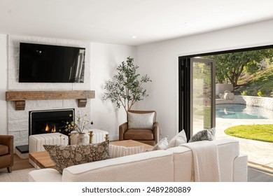 Modern living room with fireplace, TV, and open sliding door leading to a pool in a backyard.