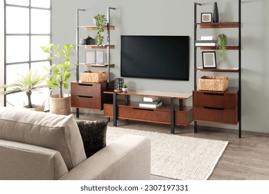 A modern living room interior with a large flat screen television mounted on the wall and contemporary shelving units - Shutterstock ID 2307197331