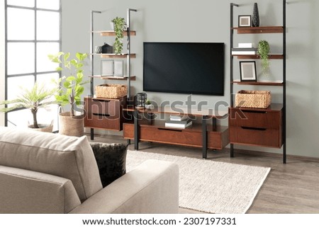 A modern living room interior with a large flat screen television mounted on the wall and contemporary shelving units