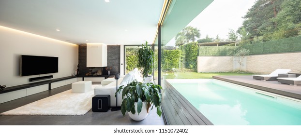 Modernes Wohnzimmer mit Blick auf den Garten und den Pool. Niemand drinnen