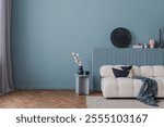 Modern living room in serene blue tones with a cozy white sofa, abstract decor, and a minimalist side table arrangement.