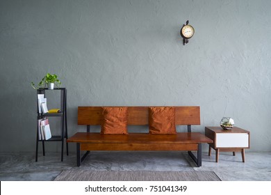 Modern Living Room With Wooden Bench Sofa ,green Plant , Wooden Tea Table And Clock. Cement Floor And Concrete Wall , Interior Design With Loft Style .