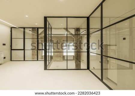 Modern loft apartment with vintage wooden beams and pillars, exposed brick walls, glass partitions with black metal frames, smooth white concrete floors and electric radiators