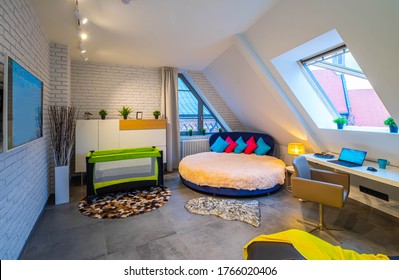 Modern Loft Interior Of Bedroom In Apartment. Roof Window. Round Bed. Workplace. TV On The Brick Wall. Playpen. Home Decor.