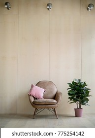 Modern Loft Living Room With Plywood Wall And Wooden Floor, Suede Beige Armchair With Pink Pillow And Green Tree Plant. Lamps On The Wall Above. Mock Up Interior Photo Simple Urban Jungle Style