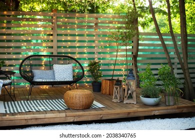 Modern lounge outdoors in backyard. Terrace house with plants, wooden wall and table, comfortable sofa, armchair and lanterns. Cozy space in patio or balcony. Wooden verande with garden furniture. 
 - Shutterstock ID 2038340765