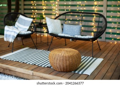 Modern Lounge Outdoors In Backyard. Terrace House With Wooden Floor, Comfortable Sofa, Armchair And Wicker Ottoman. Cozy Space In Patio Or Balcony For Relax. Wooden Veranda With Garden Furniture.
