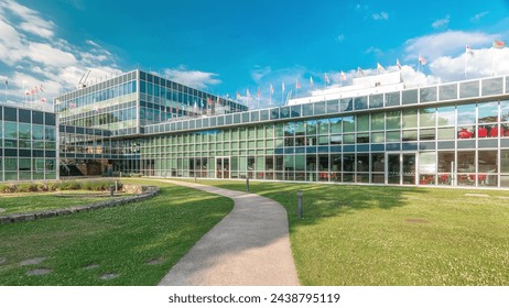 Modern low rise glass office building in business district and green lawn with path in inner yard timelapse hyperlapse. Flags of many different countries on the top of roof - Powered by Shutterstock - Get 15% off with code: PIKWIZARD15