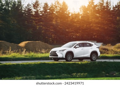 A modern and luxurious SUV car travels on an asphalt road with a breathtaking landscape of a golden sunset sky. - Powered by Shutterstock