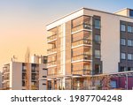 Modern luxury apartment building, block of flats with glass balconies in the sunset light. Real estate. Cozy evening ambiance in residential area in city. Glass surface of facade. Building exterior.