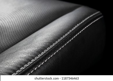 Modern luxury car black leather interior. Part of leather seat details with stitching. Interior of prestige modern car. Comfortable perforated leather seats. Black perforated leather. Car detailing