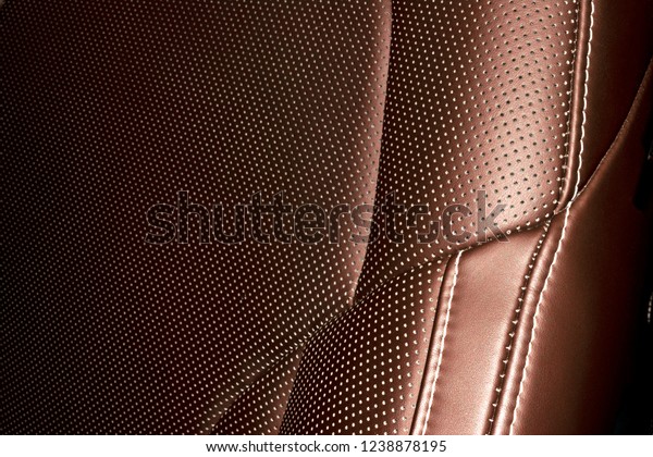 Modern luxury Car brown leather interior. Part\
of leather car seat details with white stitching. Interior of\
prestige car. Comfortable perforated leather seats. Brown\
perforated leather.