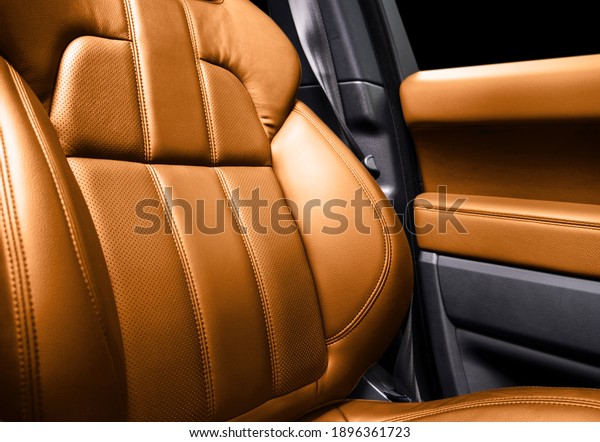 Modern luxury car brown leather interior. Part\
of orange perforated leather car seat details with white stitching.\
Interior of prestige car. Comfortable perforated leather seats.\
Perforated leather.