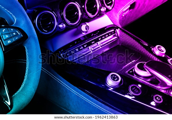 Modern\
luxury car inside in blue and pink tones. Interior of prestige\
modern car with carbon panels. Comfortable leather seats. Steering\
wheel and dashboard. automatic gear stick shift.\
