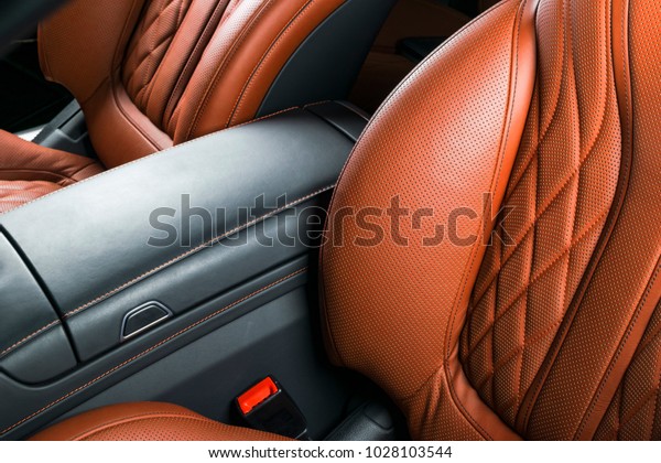 Modern Luxury\
car inside. Interior of prestige modern car. Comfortable leather\
brown seats. Orange perforated leather cockpit. Automatic\
transmission. Modern car interior\
details