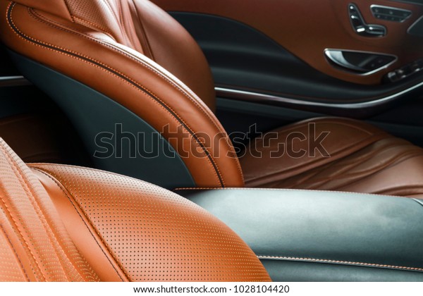 Modern Luxury car inside. Interior of prestige\
modern car. Comfortable leather brown seats. Orange perforated\
leather. Modern car interior\
details