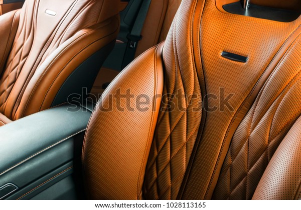 Modern Luxury car inside. Interior of prestige\
modern car. Comfortable leather brown seats. Orange perforated\
leather cockpit with isolated Black background. Modern car interior\
details