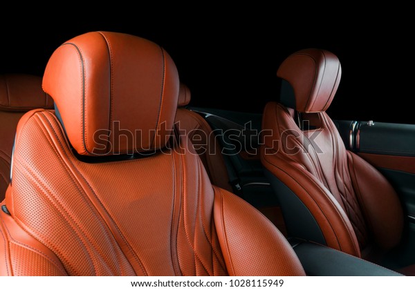 Modern Luxury car inside. Interior of prestige\
modern car. Comfortable leather brown seats. Orange perforated\
leather cockpit with isolated Black background. Modern car interior\
details