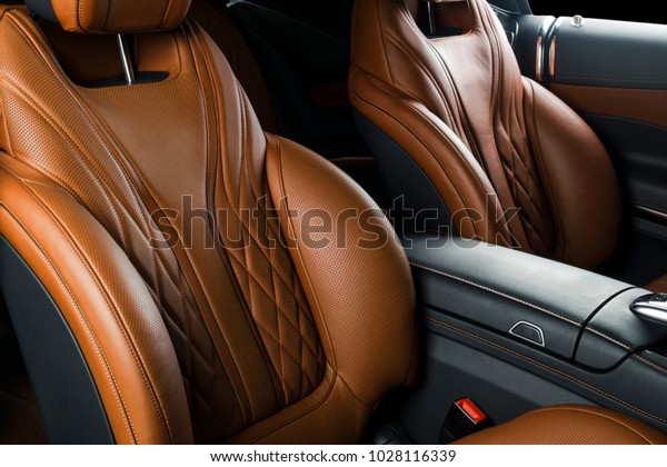 Modern\
Luxury car inside. Interior of prestige modern car. Comfortable\
leather seats. Orange perforated leather cockpit with isolated\
Black background. Modern car interior\
details