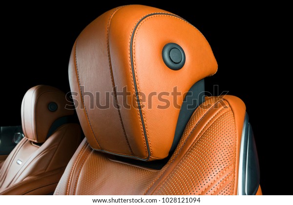 Modern\
Luxury car inside. Interior of prestige modern car. Comfortable\
leather seats. Orange perforated leather cockpit with isolated\
Black background. Modern car interior\
details