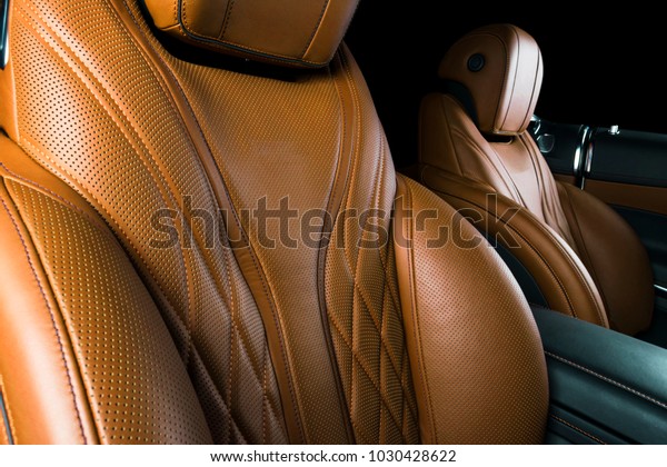 Modern Luxury car\
inside. Interior of prestige modern car. Comfortable leather seats.\
Brown perforated leather cockpit with isolated Black background.\
Modern car interior\
details