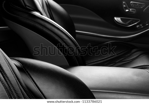 Modern Luxury car inside. Interior of\
prestige modern car. Comfortable leather red seats. Perforated\
leather. Modern car interior details. Black and\
white