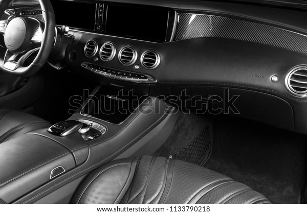 Modern Luxury car inside. Interior of prestige\
modern car. Comfortable leather seats. Red perforated leather\
cockpit. Modern car interior details. Dashboard and steering wheel.\
Black and white