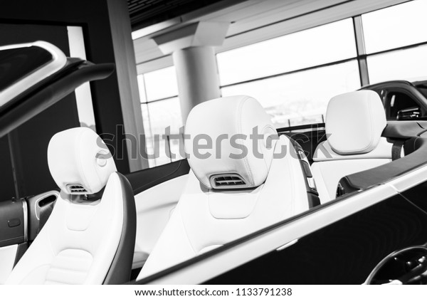 Modern Luxury\
car inside. Interior of prestige modern cabriolet car. Comfortable\
leather seats. White perforated leather. Modern car interior\
details. Cabrio. Black and\
white
