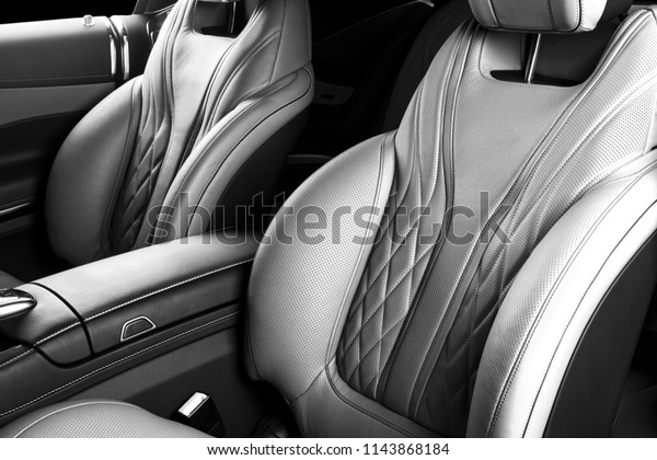 Modern Luxury car inside. Interior of prestige\
modern car. Comfortable leather seats. Perforated leather with\
isolated Black background. Modern car interior. Car detailing.\
Black and white