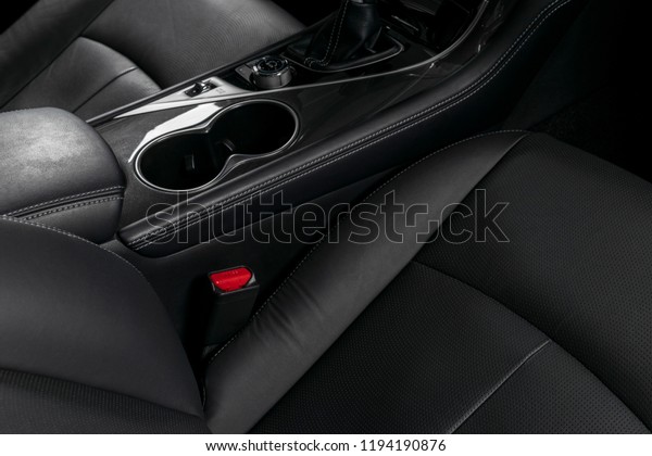 Modern Luxury car inside. Interior of prestige\
car. Comfortable leather seats with stitching. Black perforated\
leather cockpit. Steering wheel and dashboard. Automatic gear stick\
shift. Car detailing