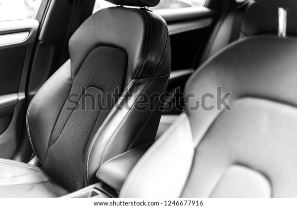 Modern Luxury car inside. Interior of prestige car.\
Comfortable leather seats. Perforated leather cockpit. Steering\
wheel and dashboard. Automatic gear stick shift. Car detailing.\
Black and white