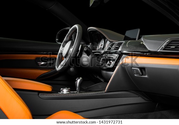 Modern luxury car\
Interior - steering wheel, shift lever and dashboard. Car interior\
luxury inside. Steering wheel, dashboard, speedometer, display.\
Orange leather cockpit
