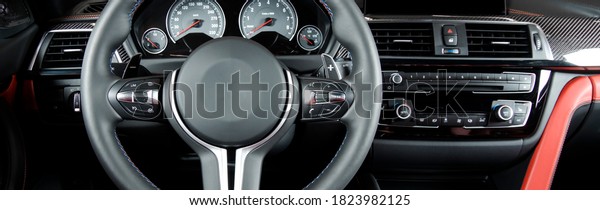 Modern luxury\
car Interior - steering wheel, shift lever and dashboard. Car\
interior luxury.Steering wheel, dashboard, speedometer, display.\
Red and black perforated\
leather.