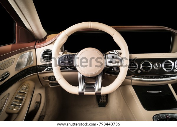 Modern luxury car Interior - steering wheel,\
shift lever and dashboard. Car interior luxury. Beige comfortable\
seats, steering wheel, dashboard, speedometer, display. Red and\
white perforated\
leather.