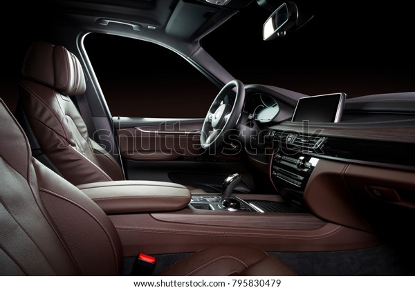 Modern luxury car Interior - steering wheel,\
shift lever and dashboard. Car interior luxury. Beige comfortable\
seats, steering wheel, dashboard, speedometer, display. Brown\
perforated leather.