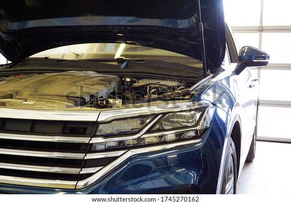 Modern luxury car with an open hood\
in the service station. In the photo the front of the car, close-up\
headlight. Service, repair, car diagnostics\
Concept.