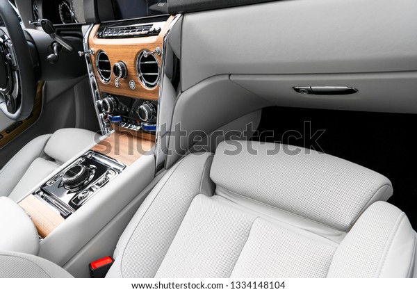 Modern luxury car white leather interior with\
natural wood panel. Part of leather  seat details with stitching.\
Interior of prestige modern car. White perforated leather. Car\
detailing. Car inside