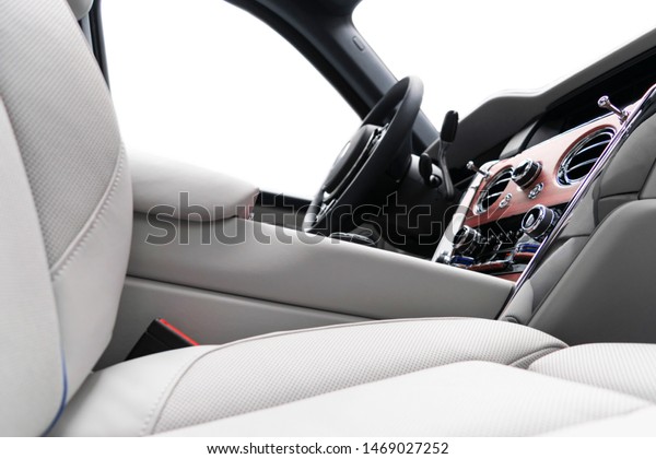 Modern luxury car white leather interior with\
natural wood panel. Part of leather seat details with stitching.\
Interior of prestige modern car. White perforated leather. Car\
detailing. Car inside