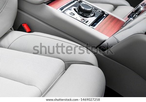 Modern luxury car white leather interior with
natural wood panel. Part of leather seat details with stitching.
Interior of prestige modern car. White perforated leather. Car
detailing. Car inside