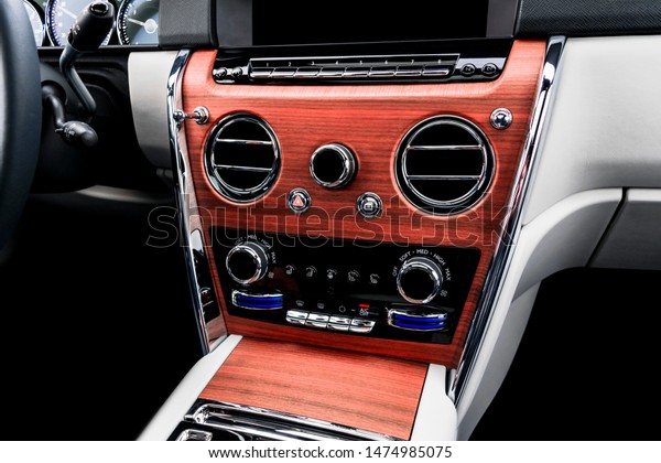 Modern luxury car white leather interior with
natural wood panel. Part of leather seat details with stitching.
Interior of prestige modern car. White perforated leather. Car
detailing. Car inside