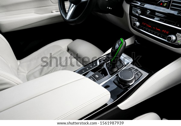 Modern luxury car white leather interior with\
natural wood panel. Part of leather car seat details with\
stitching. Interior with dashboard. White perforated leather. Car\
detailing. Car inside