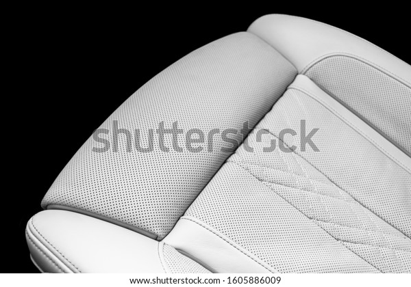 Modern luxury Car white leather interior. Part of\
perforated leather car seat details. White Perforated leather\
texture background. Texture, artificial leather with stitching.\
Perforated seats