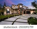 Modern luxury home exterior with a beautifully landscaped front yard and driveway at dusk.