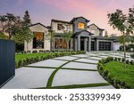 Modern luxury home exterior with a well-manicured lawn, geometric driveway, and sunset sky in the background.