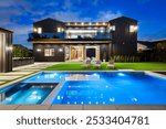 Modern luxury home with swimming pool and outdoor seating area at dusk, showcasing contemporary architecture and stylish design.