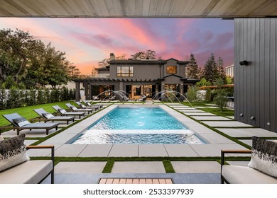 Modern luxury home with a swimming pool and sun loungers at sunset, featuring a well-manicured garden and outdoor seating area. - Powered by Shutterstock