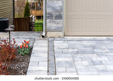 Modern Luxury Landscaping Shows A  Precast Paver Driveway With Pattern And Gravel And Concrete Slab Steps Along The Sideyard.