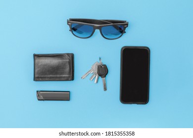 modern man items don't forget to carry in top view on table cell phone sunglasses lighter wallet keys in black on blue background with copy space left