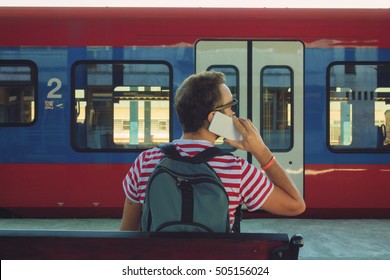 Modern man using cellphone on train station.